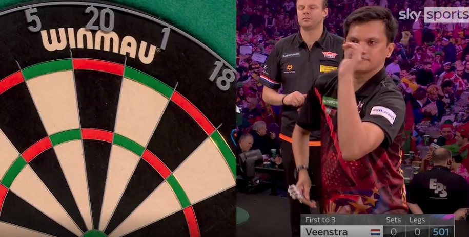 A darts player throws a dart at a dartboard.