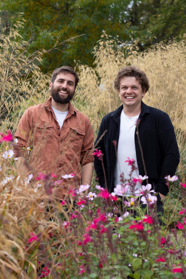 Two men smiling in a garden.