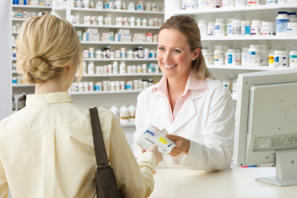 Pharmacist handing prescription to customer.