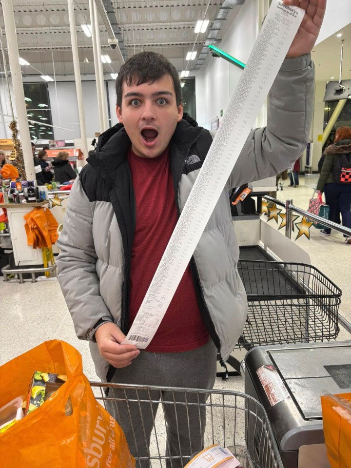 Person holding extremely long Sainsbury's receipt after a large grocery shop.