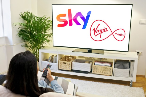 Woman watching TV displaying Sky and Virgin Media logos.