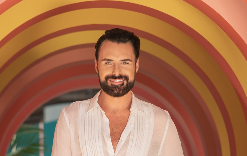 Rylan Clark, smiling, standing in a colorful archway.