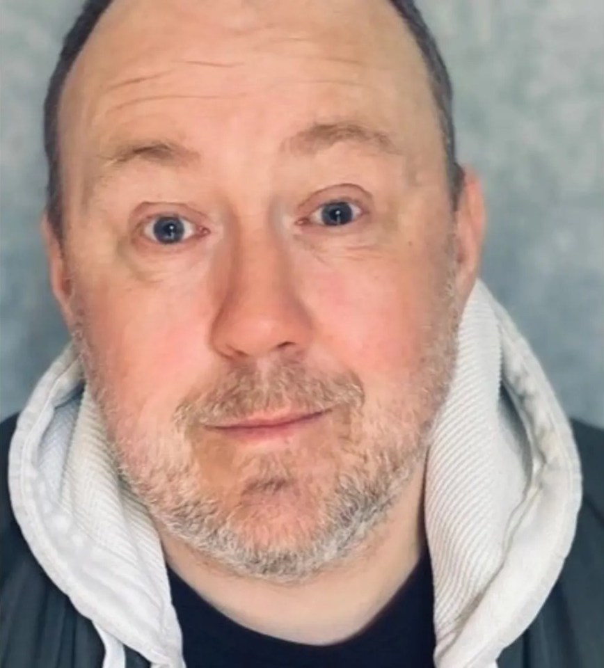 Headshot of a man with a beard wearing a hooded jacket.