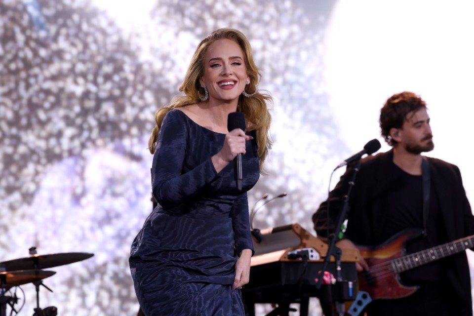 Adele performing on stage with a microphone.