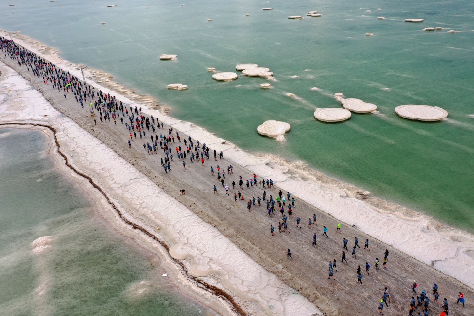 Competitors running on salty soil during the Dead Sea Marathon