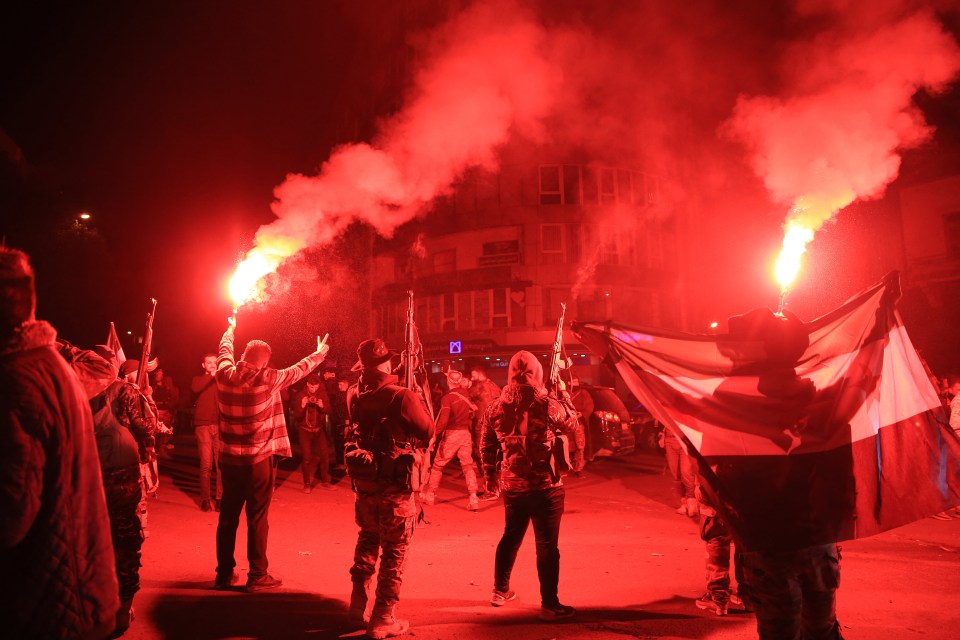 Rebel forces shoot in the air as they celebrate in the central Syrian city of Homs