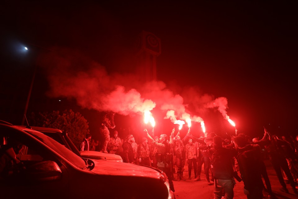 Syrian rebel fighters and locals celebrate after seizing the central city of Homs