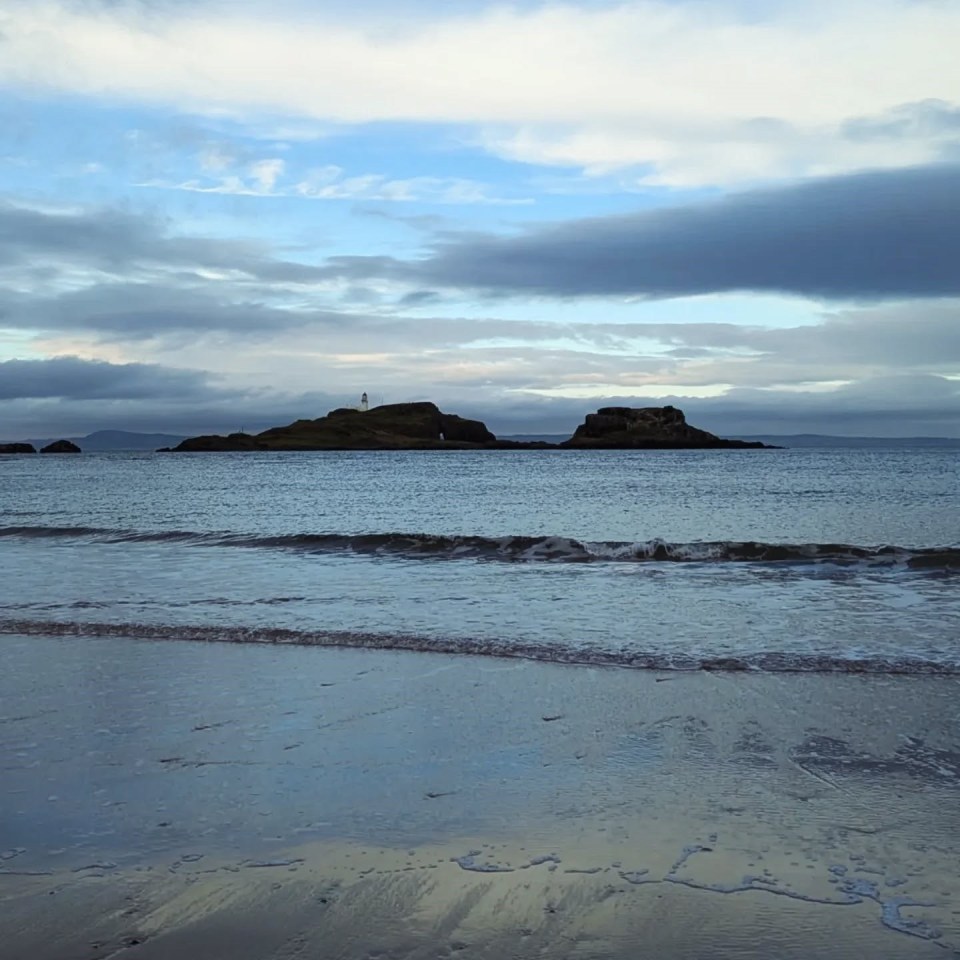 Coastal scene with a lighthouse on a small island.