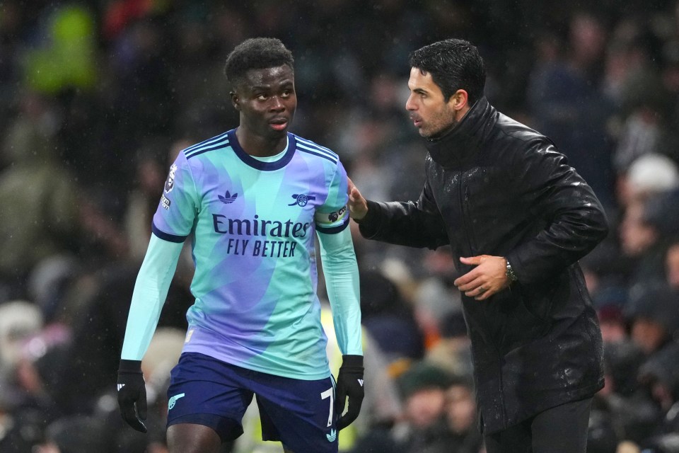 Mikel Arteta speaks with Bukayo Saka during a soccer match.