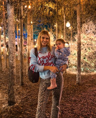 Woman in leopard print pants holding a toddler in a winter wonderland setting.