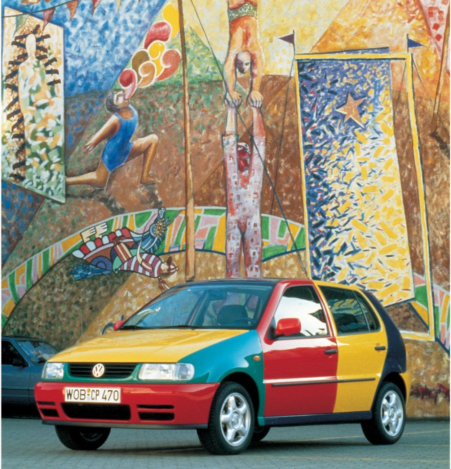 Multicolored VW Polo hatchback parked in front of a circus-themed mural.