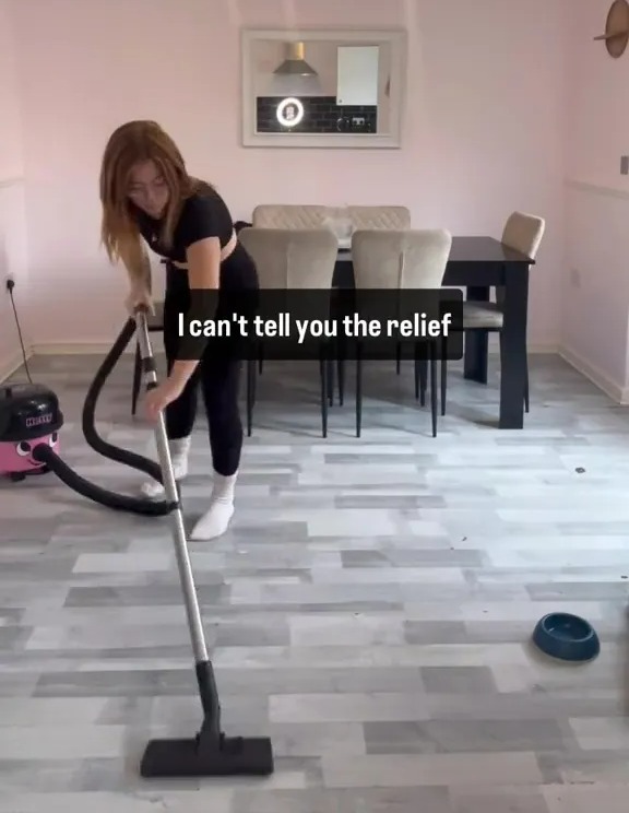 Woman vacuuming floor in dining room.