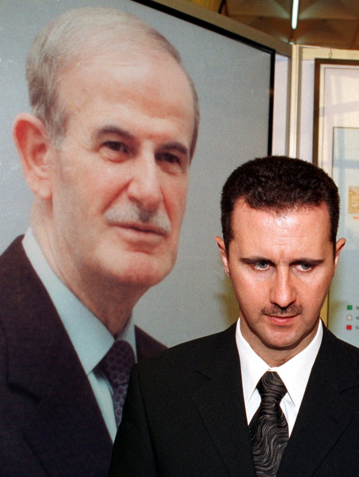 Bashar al-Assad walks past a portrait of his father