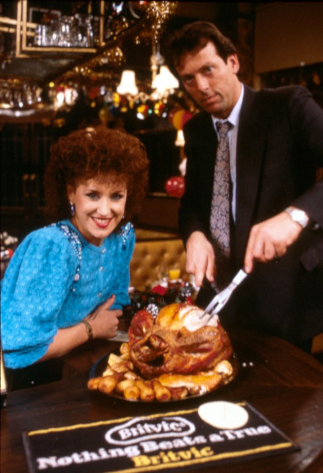 Angie Watts and Den Watts from EastEnders carving a roast chicken.