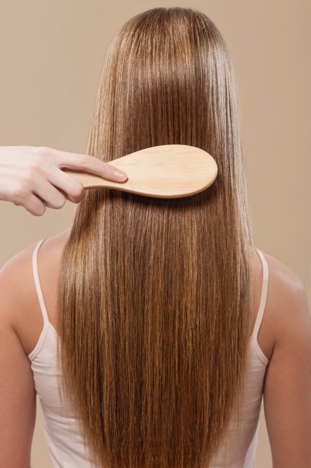 Woman brushing long, straight brown hair.