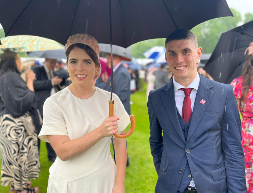 A woman and a man stand under an umbrella.