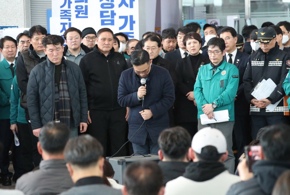 A Jeju Air official (centre) bows his head and apologises to the bereaved families of passengers