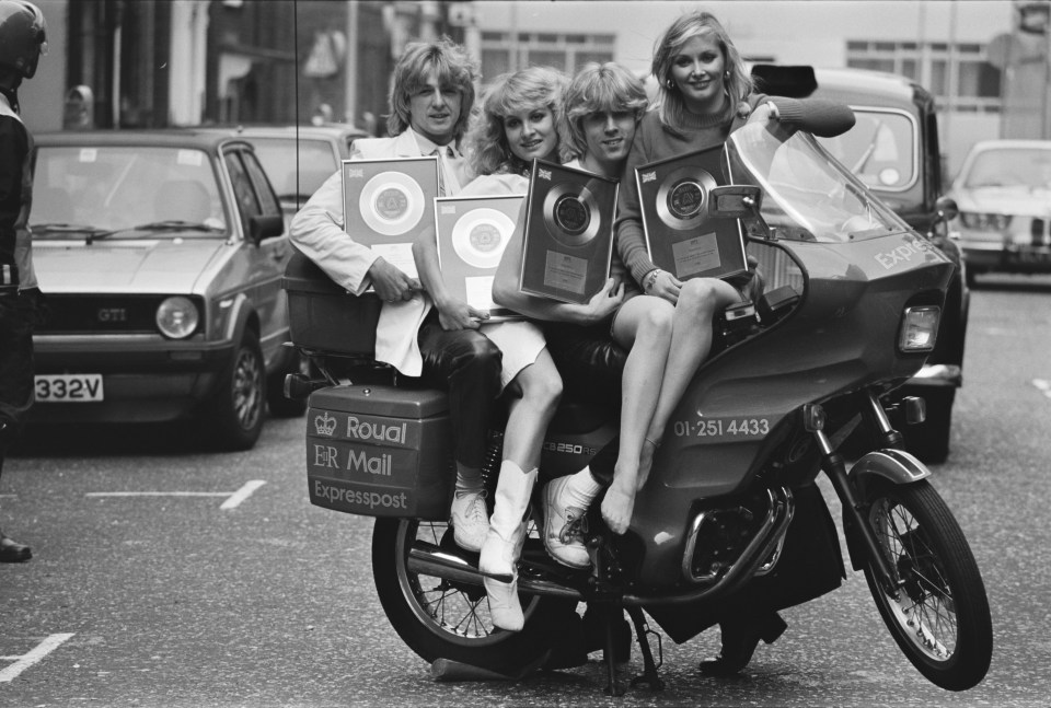 Bucks Fizz on a motorbike with their gold record awards.