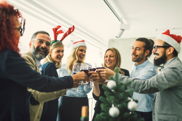 Businesspeople celebrating Christmas at work, toasting with wine.