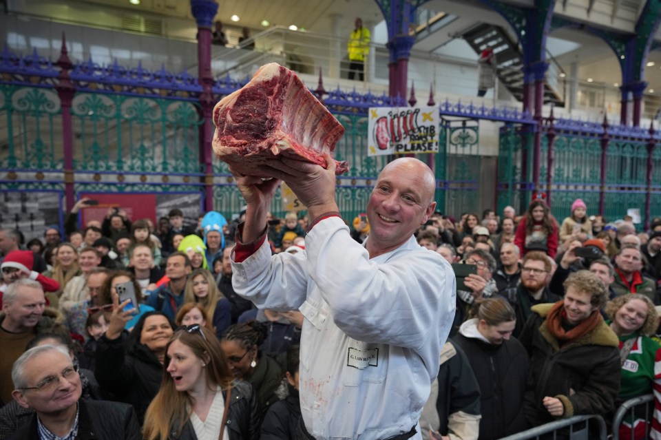 A butcher displays a large cut of meat at a Christmas meat auction.