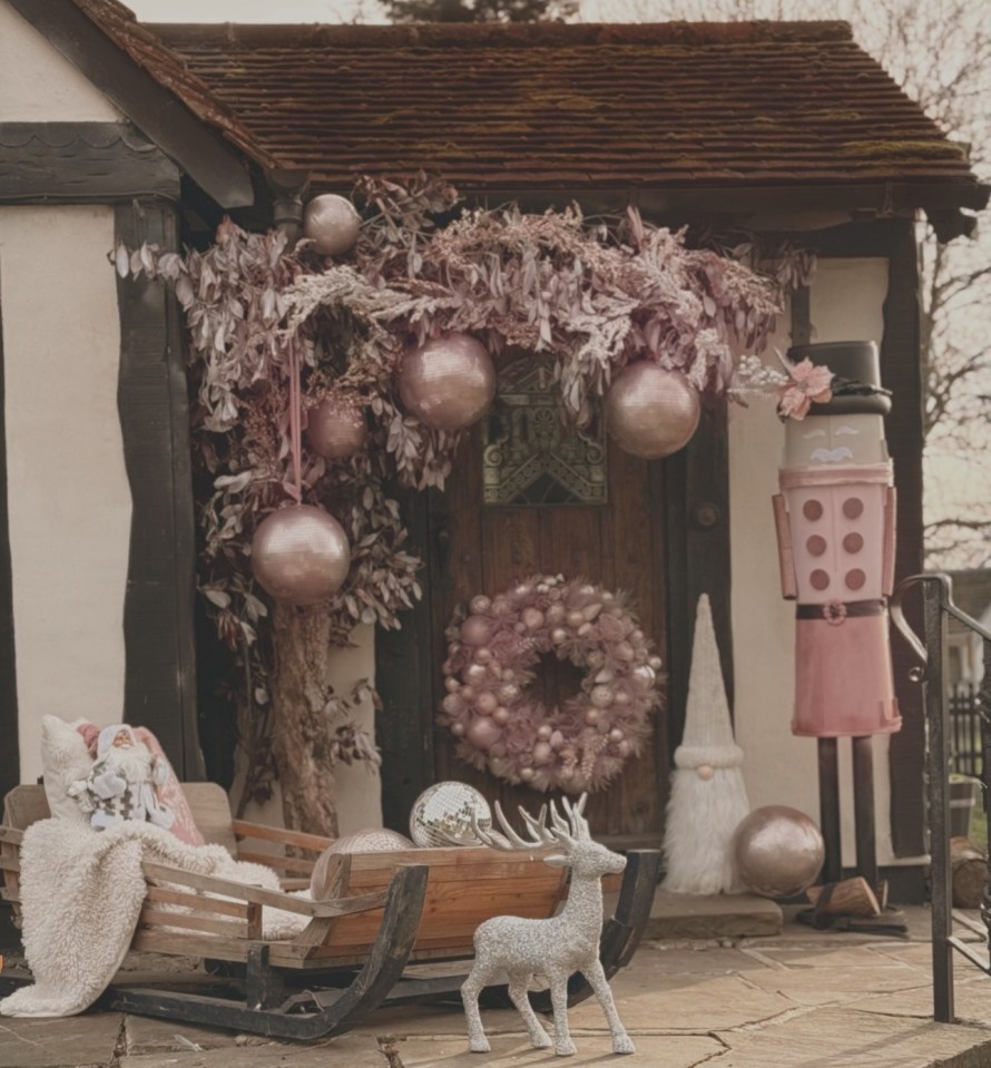 Pink and silver Christmas decorations on a house's front porch.