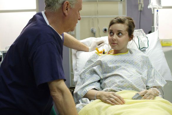 A doctor speaks with a young female patient in a hospital bed.