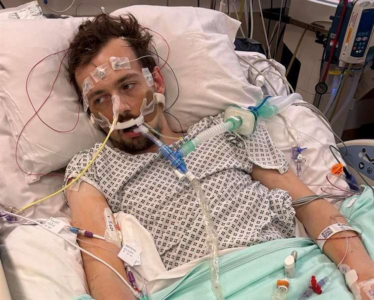 Young man in hospital bed with medical equipment.