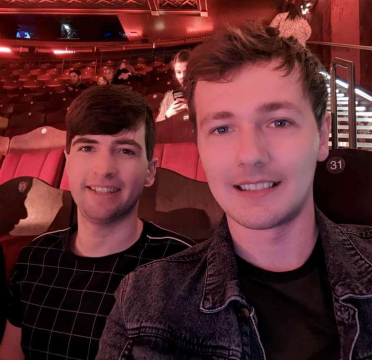 Two young men seated together in a theater.