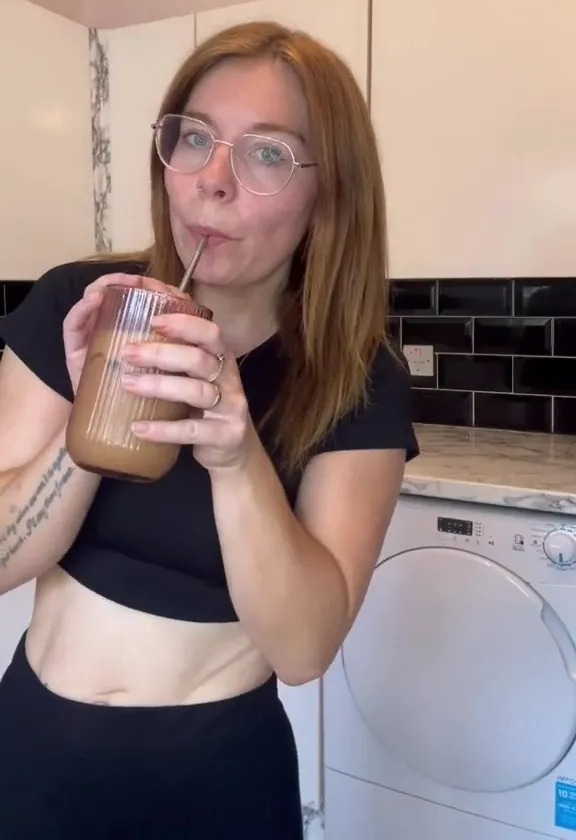 Woman drinking iced coffee in her kitchen.