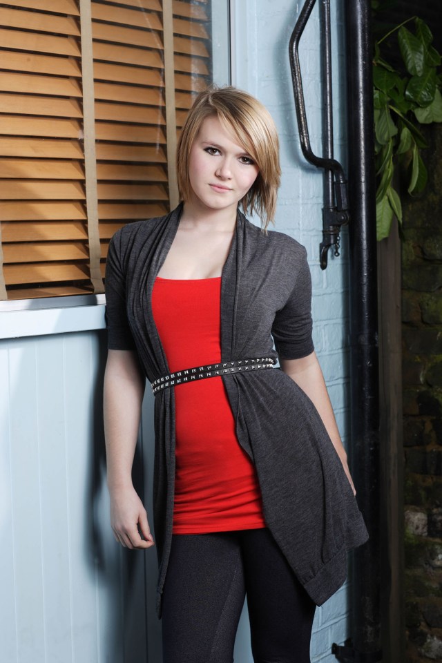 Portrait of a young woman wearing a red top and gray cardigan.