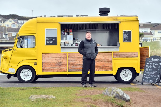 Chef Jamie O'Leary stands by his yellow food truck, which serves lobster thermidor and other items.