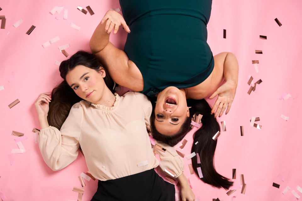 A mother and daughter lie on a pink background surrounded by confetti.