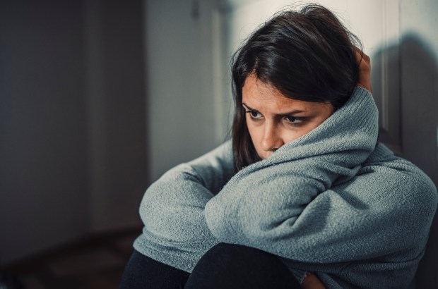 Young woman sitting alone, appearing distraught.