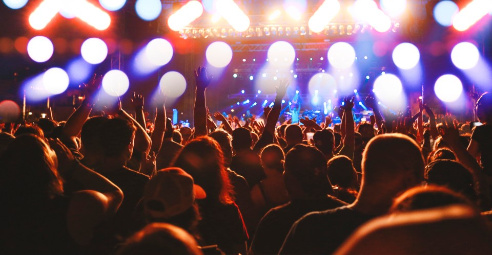 Concert crowd cheering with arms raised.