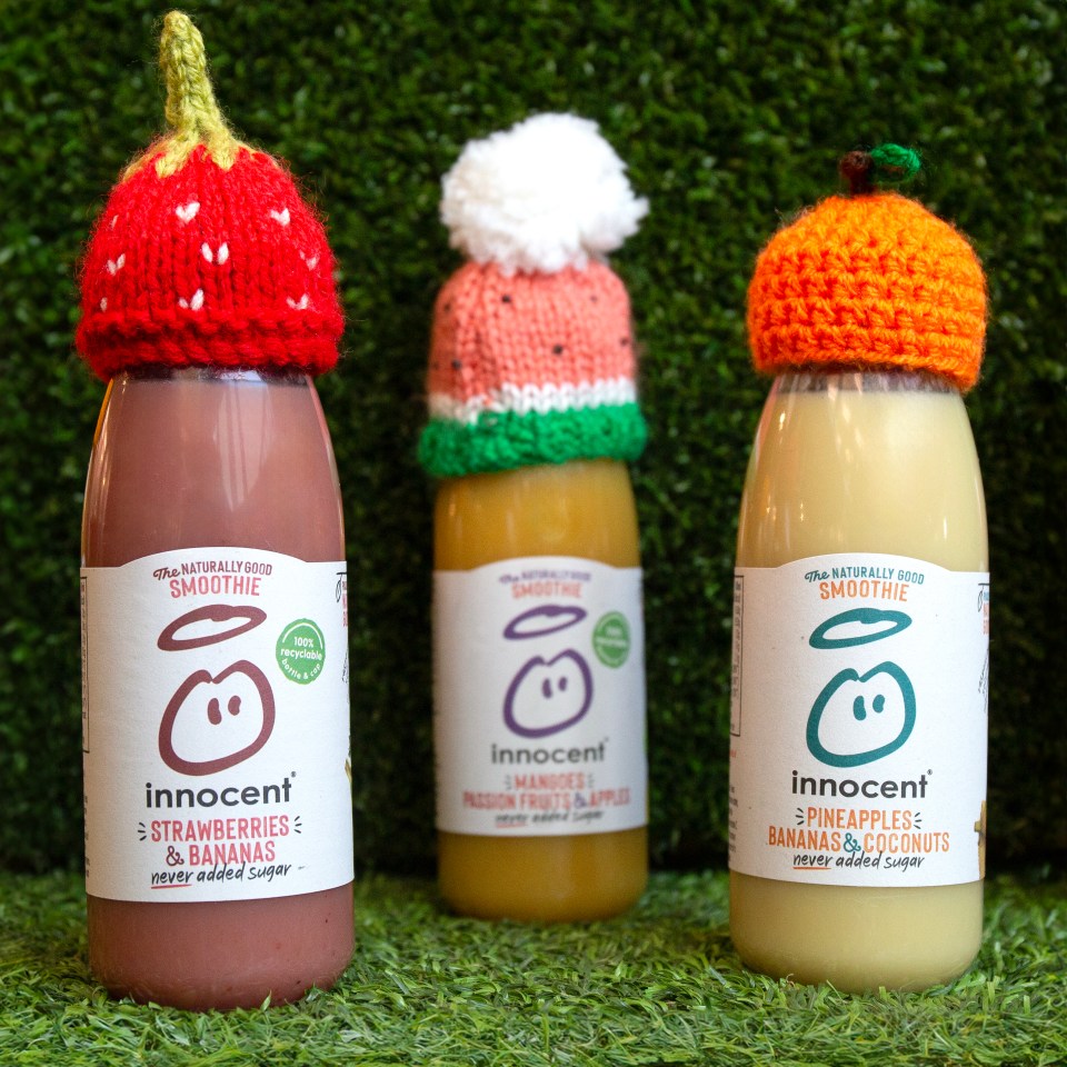 Three innocent smoothie bottles wearing hand-knitted hats for a charity fundraiser.