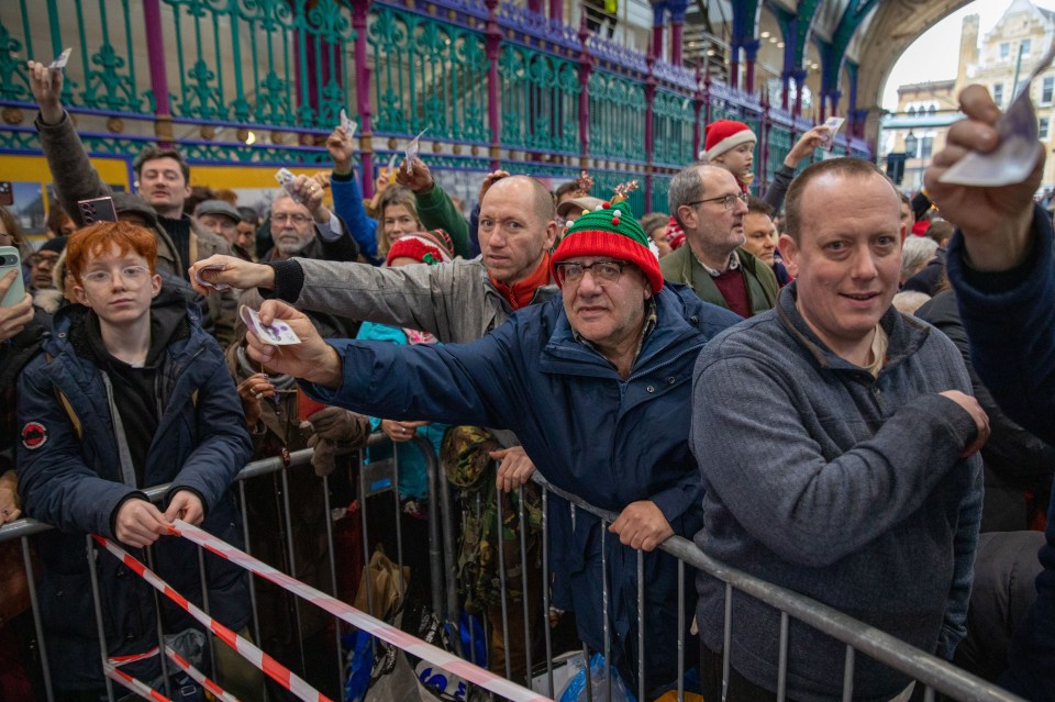 Crowd at a meat auction holding up cash to bid.