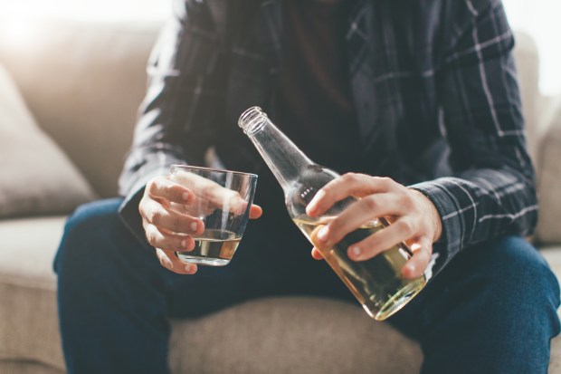 Depressed man pouring alcohol into a glass.