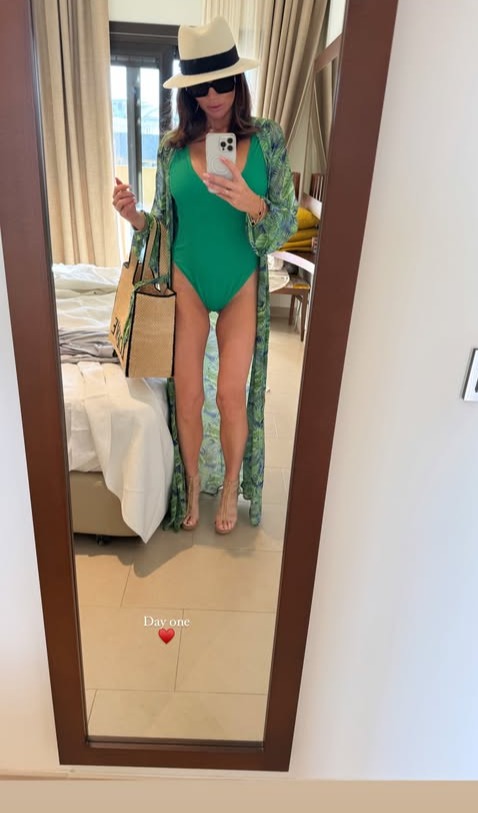 Woman in green swimsuit and patterned robe taking a selfie in a mirror.