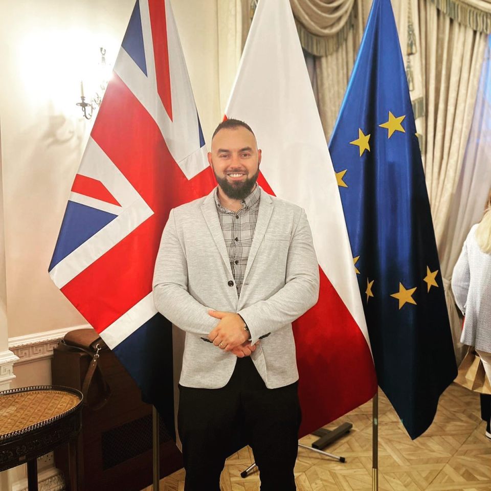 Karol Olender, bodybuilder, standing between the British and Polish flags.