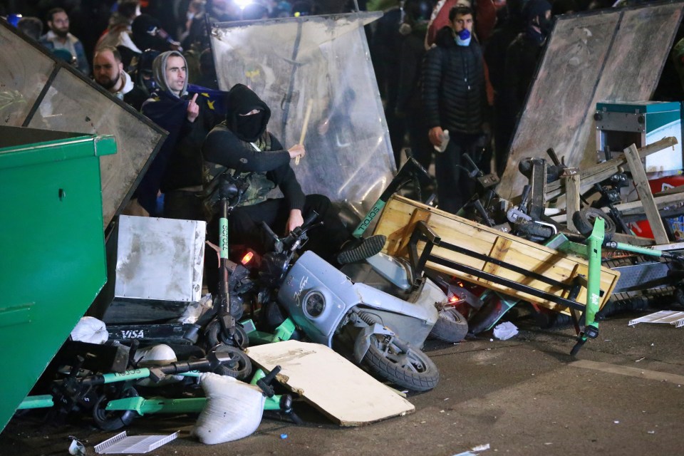 Demonstrators sit at a barricade during a rally outside the parliament’s building to protest the government’s decision to suspend negotiations on joining the European Union