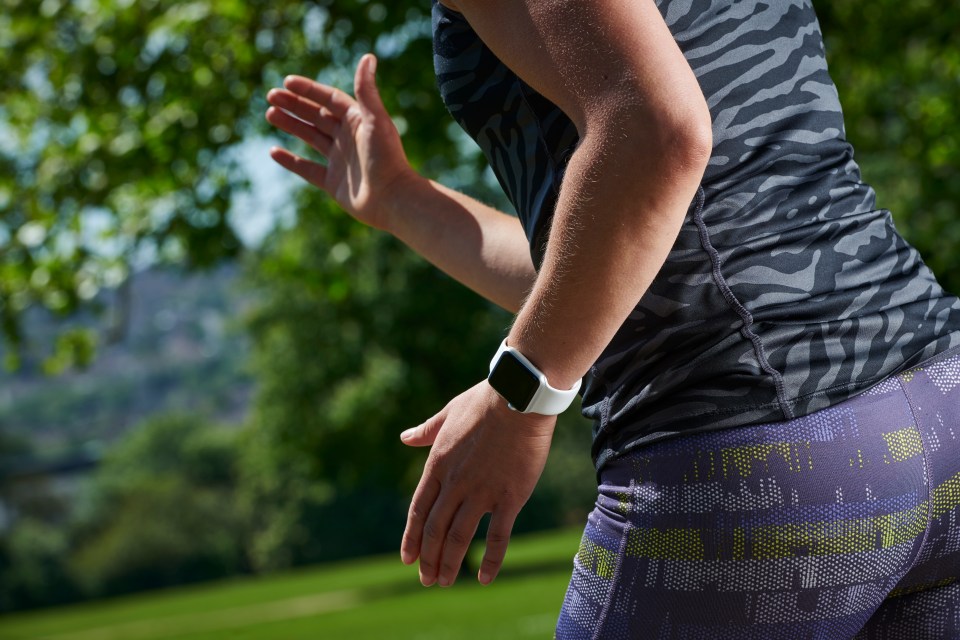 Woman wearing a smartwatch while jogging outdoors.