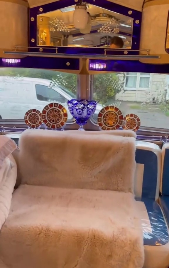 Interior of a luxury caravan, showing a plush seat and decorative china.