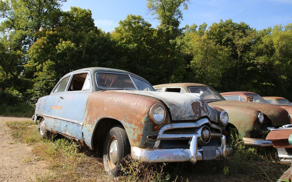 Rusty vintage cars in a junkyard.