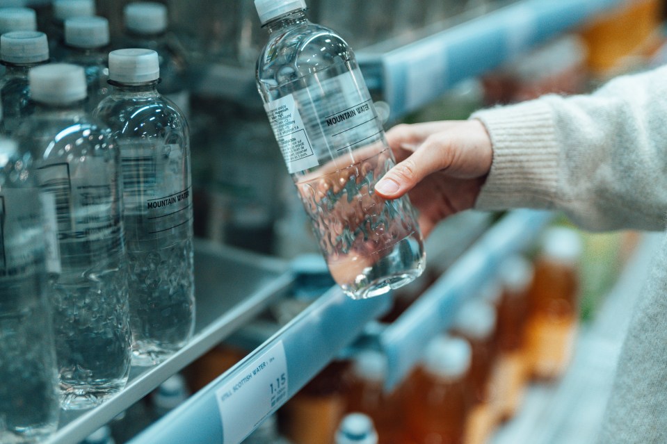 Close up shot of a woman buying bottled water in supermarket. BPA Free concept.