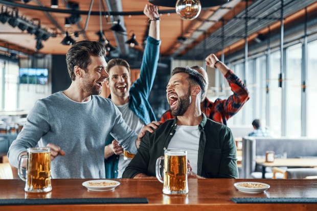 Excited men watching a sports game at a bar.