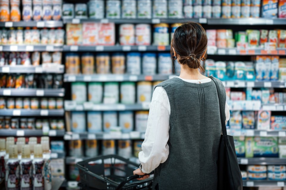 A mother shopping for baby products in a supermarket.