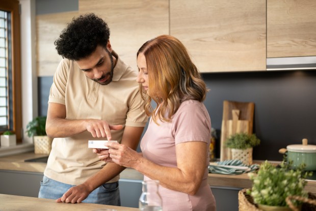 Mother with her son talking while holding medicine box in kitchen.