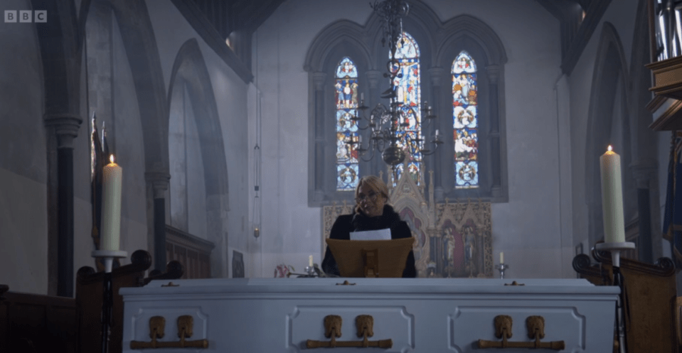 A woman delivers a eulogy at a funeral in a church.