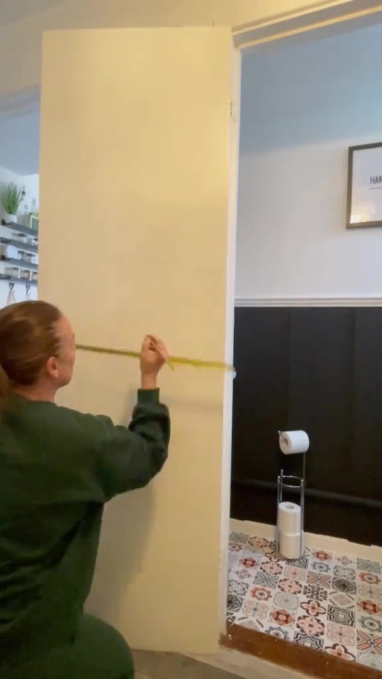 Person measuring a door frame with a tape measure.