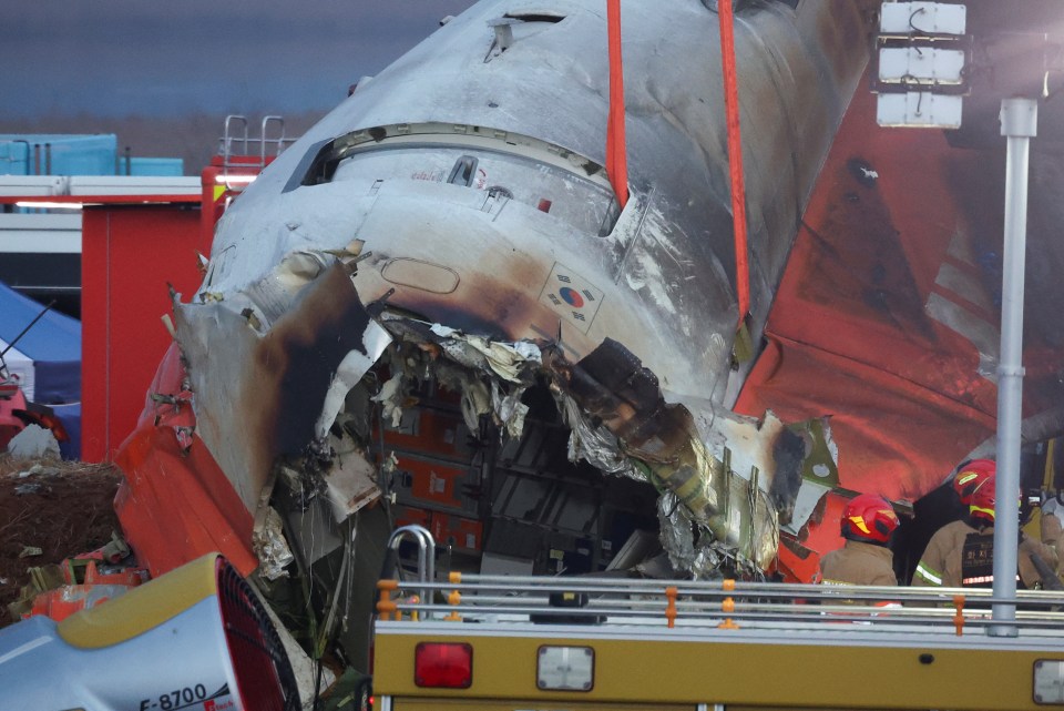 Rescue workers lifting the wreckage of a damaged aircraft.